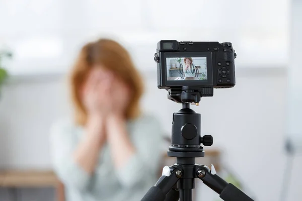 Intreepupil foto van bloemist vrouw die betrekking hebben op gezicht met handen aan tafel met florarium. — Stockfoto