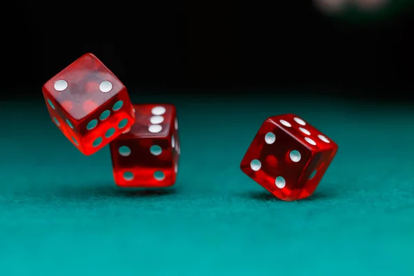 Image of several red dice falling on green table on black background — Stock Photo, Image