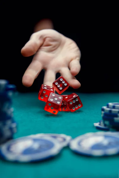 Afbeelding van man vijf rode dobbelstenen gooien op tafel met chips in casino — Stockfoto