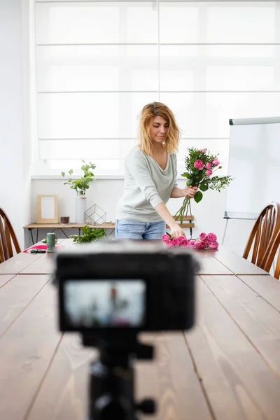 Foto van jong meisje bloemist componeren boeket van roze bloemen. — Stockfoto