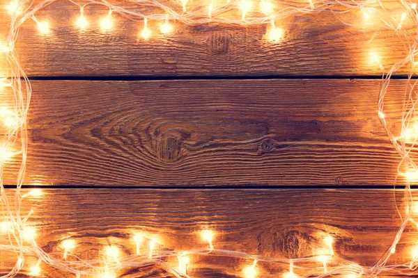 Foto de superficie de madera con guirnalda ardiente alrededor del perímetro . —  Fotos de Stock