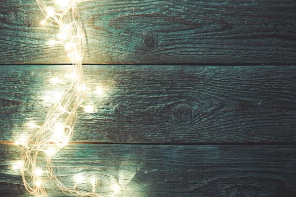 Photo of blue wooden table with burning garland on side — Stock Photo, Image