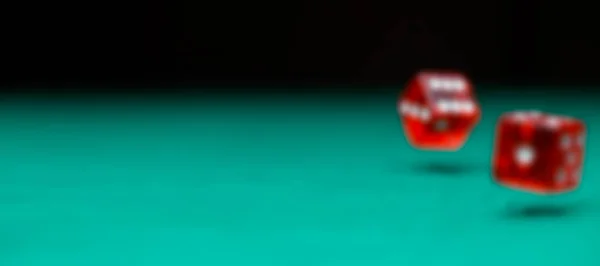 Defocused photo of two dice falling on green table