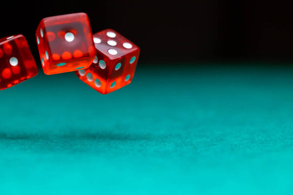Picture of several red dice falling on green table,, empty space for text