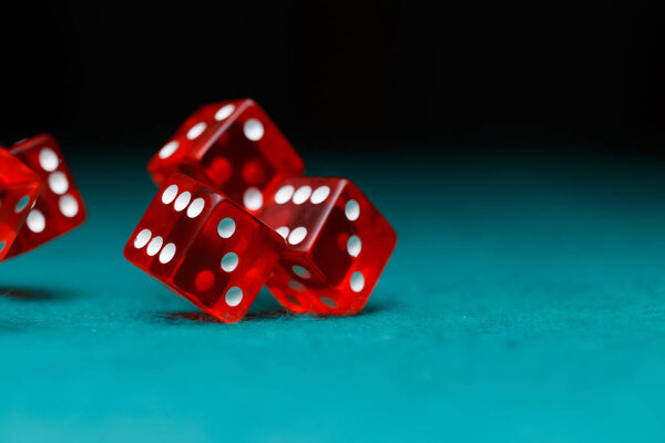 Photo of several red dice falling on green table