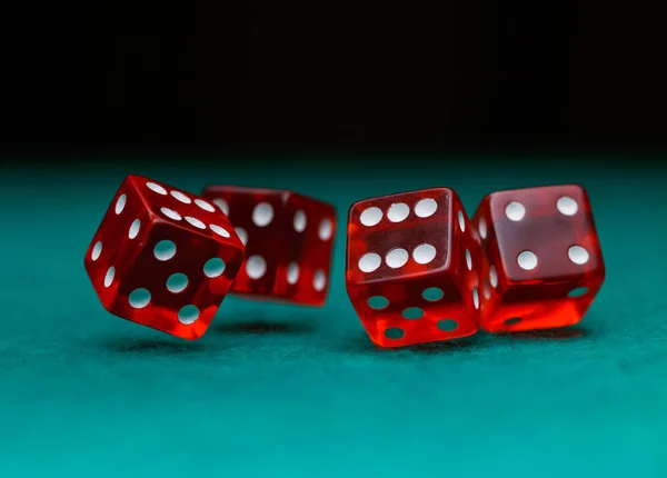 Foto van verschillende rode dobbelstenen vallen op groene tafel op zwarte achtergrond — Stockfoto