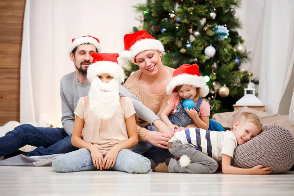 Foto de familia feliz en Santa caps en el árbol de Navidad —  Fotos de Stock