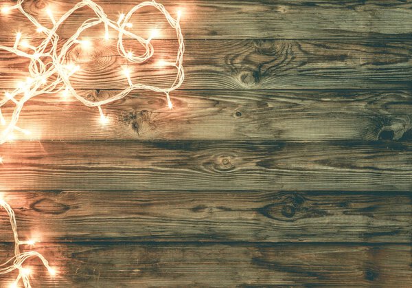 Рождественский темно-коричневый деревянный фон украшен сияющими лиями
