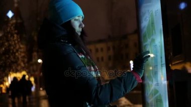 Geceleri sokakta sokak bilgi paneli kullanan kadın.