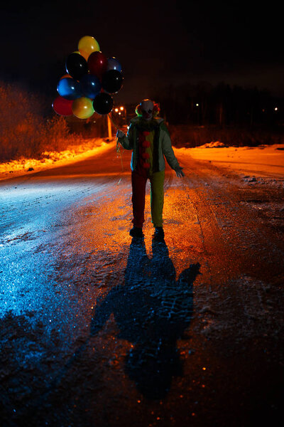Picture clown with balls in hands at night