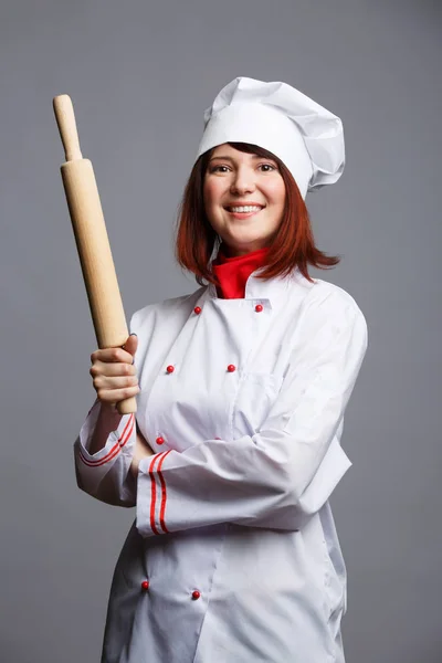 Imagem de morena cozinheiro em casaco branco e tampa com rolo de pino nas mãos — Fotografia de Stock