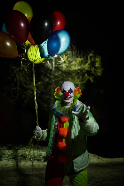 Foto av leende clown med färgglada ballonger på natten — Stockfoto