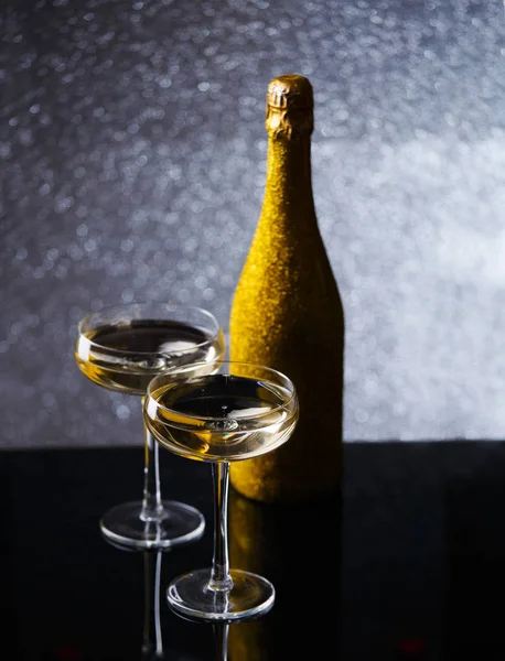 Festive photo of bottle of champagne in gold wrapper with two wine glasses — Stock Photo, Image