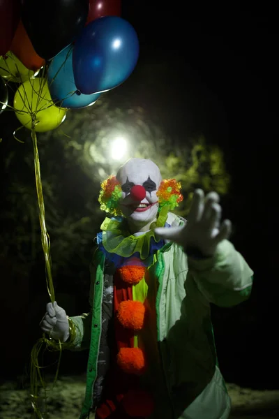 Foto av leende clown med färgglada ballonger på natten — Stockfoto