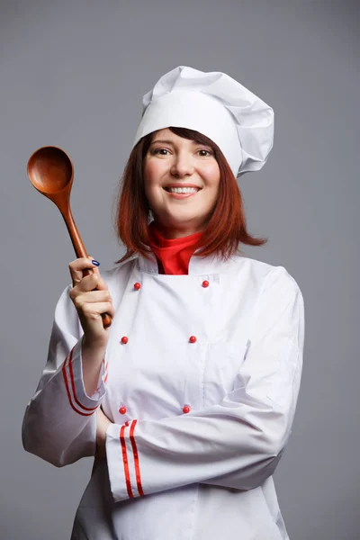 Imagen de cocinera en bata blanca y gorra con cuchara de madera — Foto de Stock