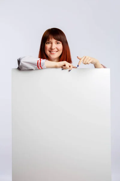 Фото брюнетки в белом халате с пустым плакатом — стоковое фото