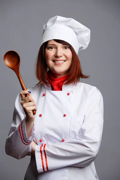 Foto da cozinheira em roupão branco e boné com colher de madeira — Fotografia de Stock