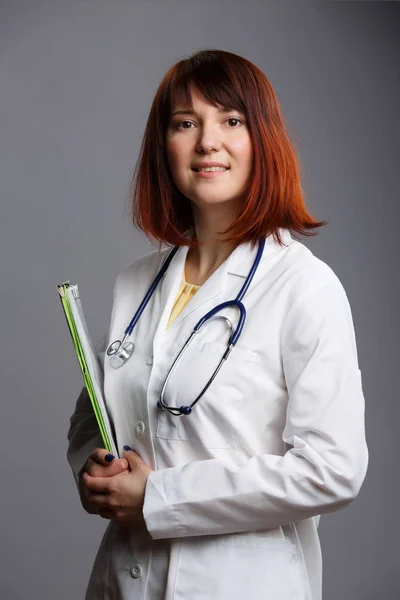 Image d'une jeune femme médecin avec phonendoscope et dossier dans les mains — Photo