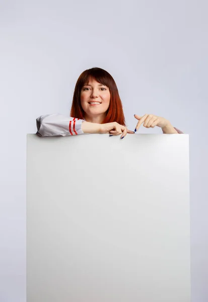 Fotografie de bucătar brunetă în halat alb cu poster gol — Fotografie, imagine de stoc