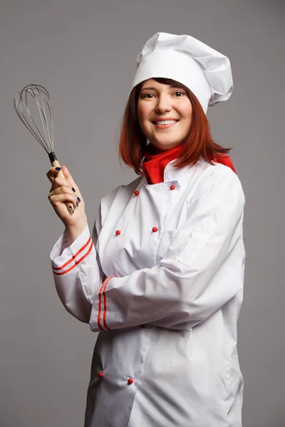 Imagen de la mujer cocinera en bata blanca y gorra con batidor en la mano — Foto de Stock