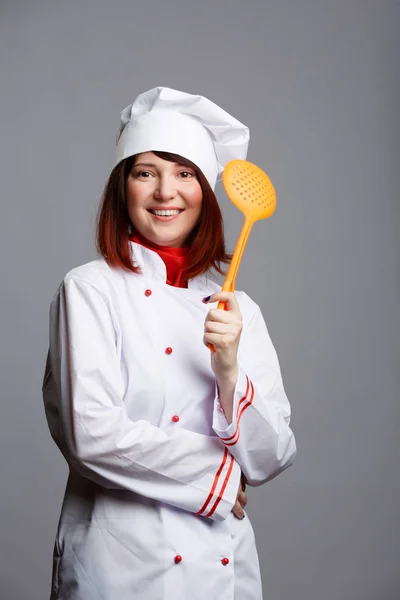 Foto de mulher cozinheiro em casaco branco e boné com colher de fenda — Fotografia de Stock