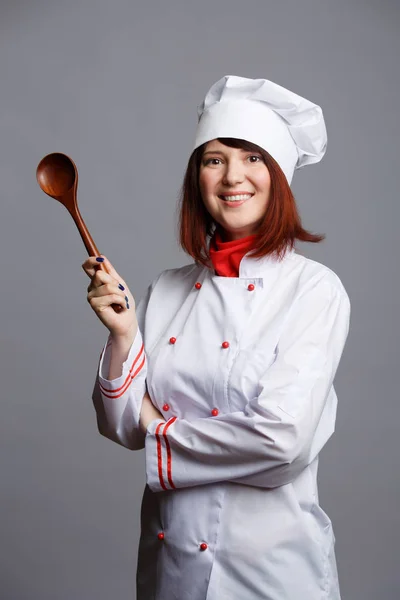 Foto de cocinera con abrigo blanco y gorra con cuchara de madera — Foto de Stock