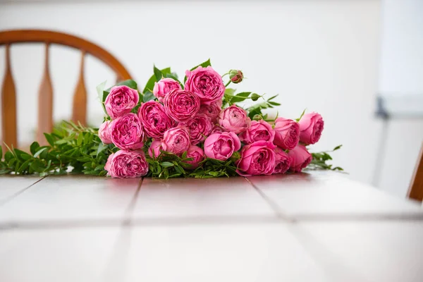 Room with white table, bouquet of pink flowers — Stock Photo, Image
