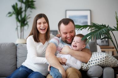 Family image of happy parents with son sitting on gray sofa clipart