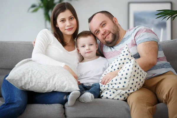 Imagem de família abraçando com filho no sofá cinza — Fotografia de Stock