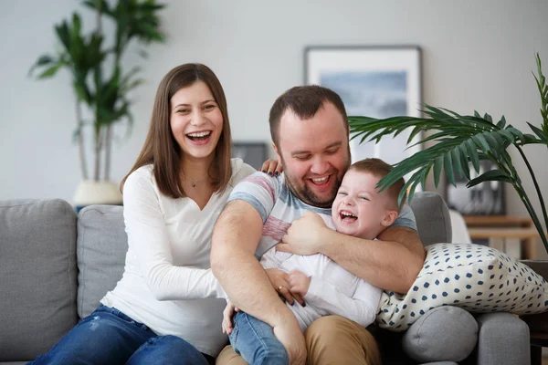 带着儿子坐在灰色沙发上的幸福父母的家庭形象 — 图库照片