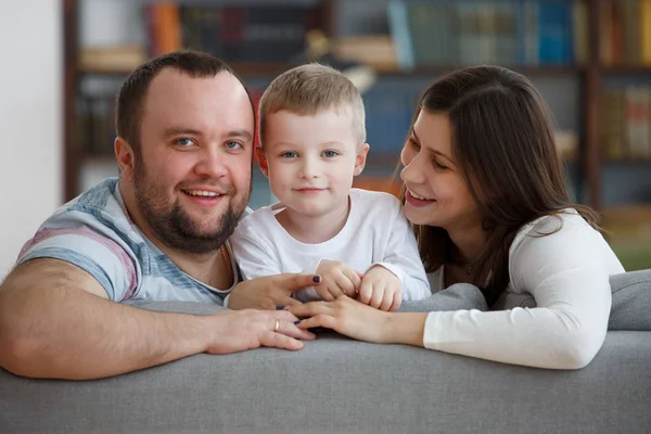 Picture of loving parents with son sitting on gray sofa — Stock Photo, Image