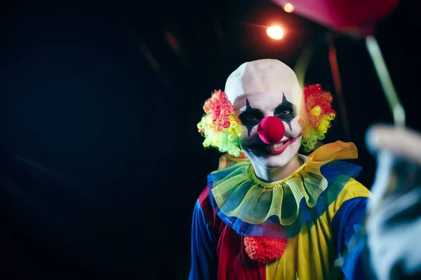 Foto von Clown mit rotem Ballon in der Nacht auf der Straße — Stockfoto
