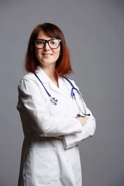 Foto de doctora sonriente en bata de laboratorio blanca y con fonendoscopio en gafas — Foto de Stock