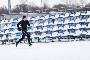 Adam spor giysilerle stadyum üzerinde çalışan resmi