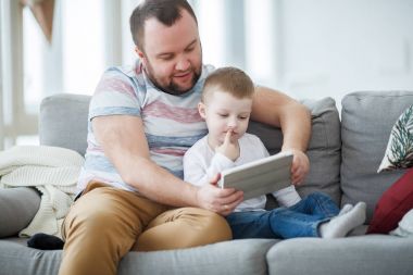 Baba ile oğlu gri üzerine oturan tablet ile resmi