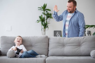 Aile fotoğrafı gri kanepe ve baba elinde kamerayla oturan genç oğlu
