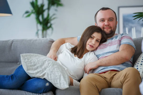 Foto von sich umarmendem Paar auf grauem Sofa — Stockfoto