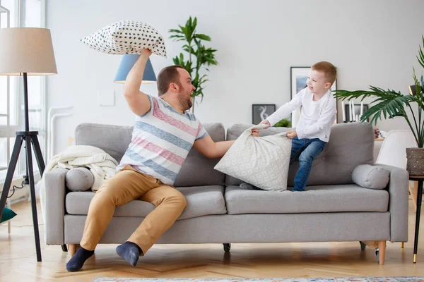 Image of father fighting with son cushions on gray sofa — Stock Photo, Image