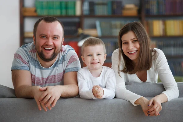 Фото улыбающихся родителей с мальчиками на сером диване — стоковое фото