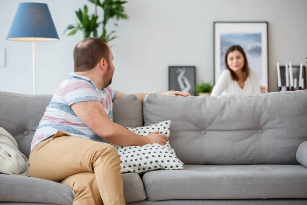 Familienfoto eines Mannes, der sich auf Sofa und Frau hinter Sofa zurücklehnt — Stockfoto