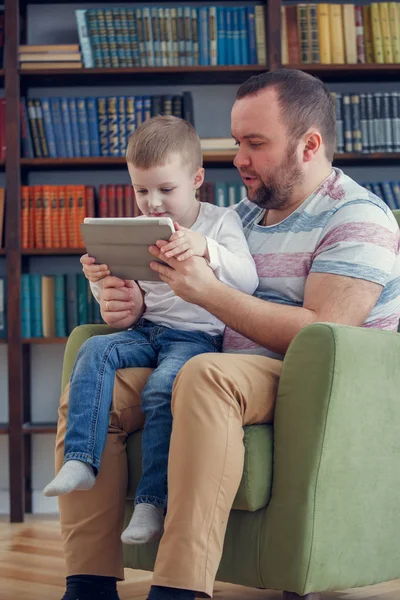 Baba ve küçük oğlu ile tablet yeşil sandalye üzerinde oturan görüntüsü — Stok fotoğraf
