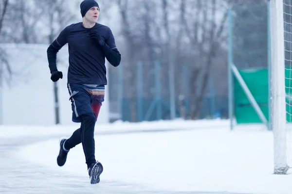 Foto eines sportlichen Mannes, der im Winter im Stadion läuft — Stockfoto
