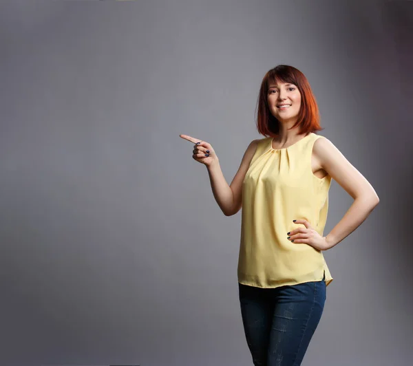 Imagen de la joven morena señalando con el dedo sobre fondo gris en blanco — Foto de Stock