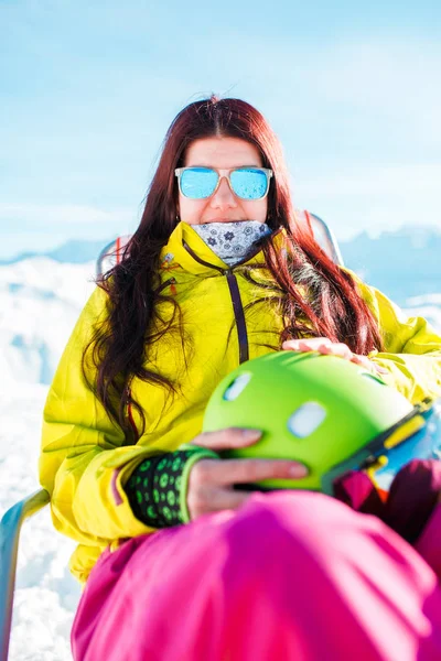 Портрет спортивной женщины с длинными волосами и шлемом, отдыхающей на кресле на зимнем курорте — стоковое фото