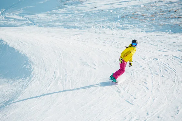 Photo of sports woman snowboarding from mountain slope