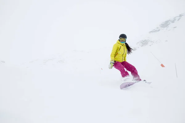 Imagen de atleta niña en casco con pelo en desarrollo, snowboard desde la ladera de la montaña —  Fotos de Stock