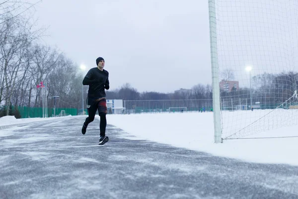 Imagem do homem desportivo correndo no estádio no inverno — Fotografia de Stock