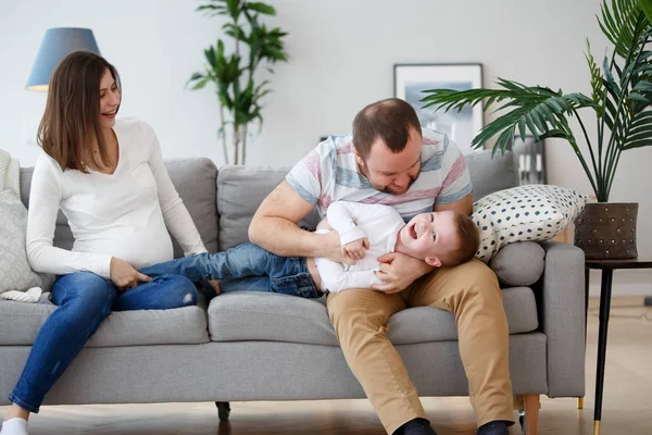 Foto von glücklicher schwangerer Frau, Mann mit Sohn auf grauem Sofa — Stockfoto