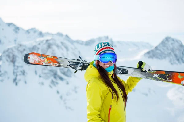 Foto van atleet vrouw met ski's op haar schouder tegen een achtergrond van besneeuwde heuvel — Stockfoto