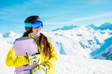 Esmer giyen kask ve maske ile snowboard karlı tepelerin arka plan üzerinde gülümseyen bir görüntü